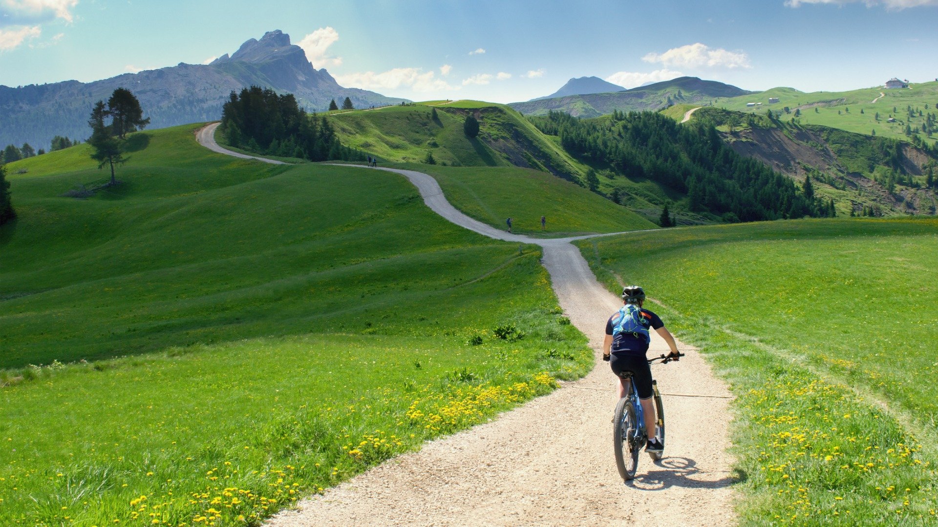 A cyclist rides along a scenic path in beautiful summer mountain scenery in the Dolomites.