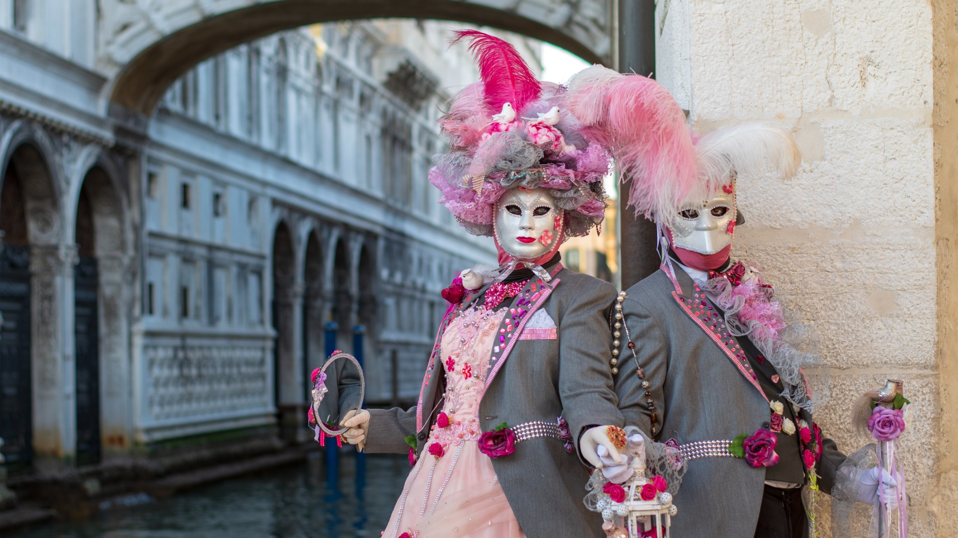 Two models dressed in Venetian Carnival costumes pose near the Bridge of Sighs.