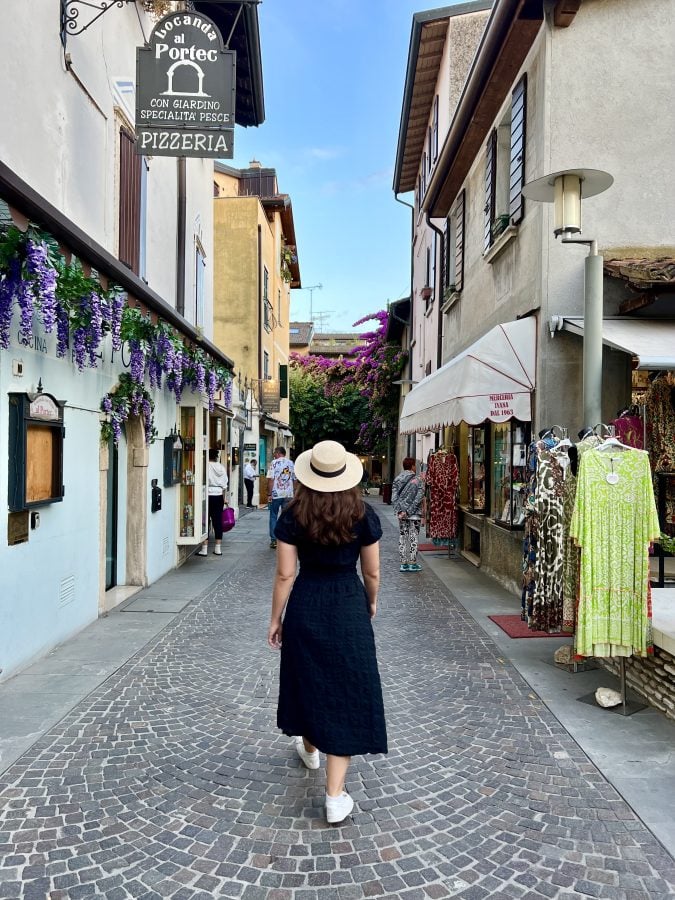 Kate Storm in a black dress and straw hat walking to dinner in Sirmione, Italy