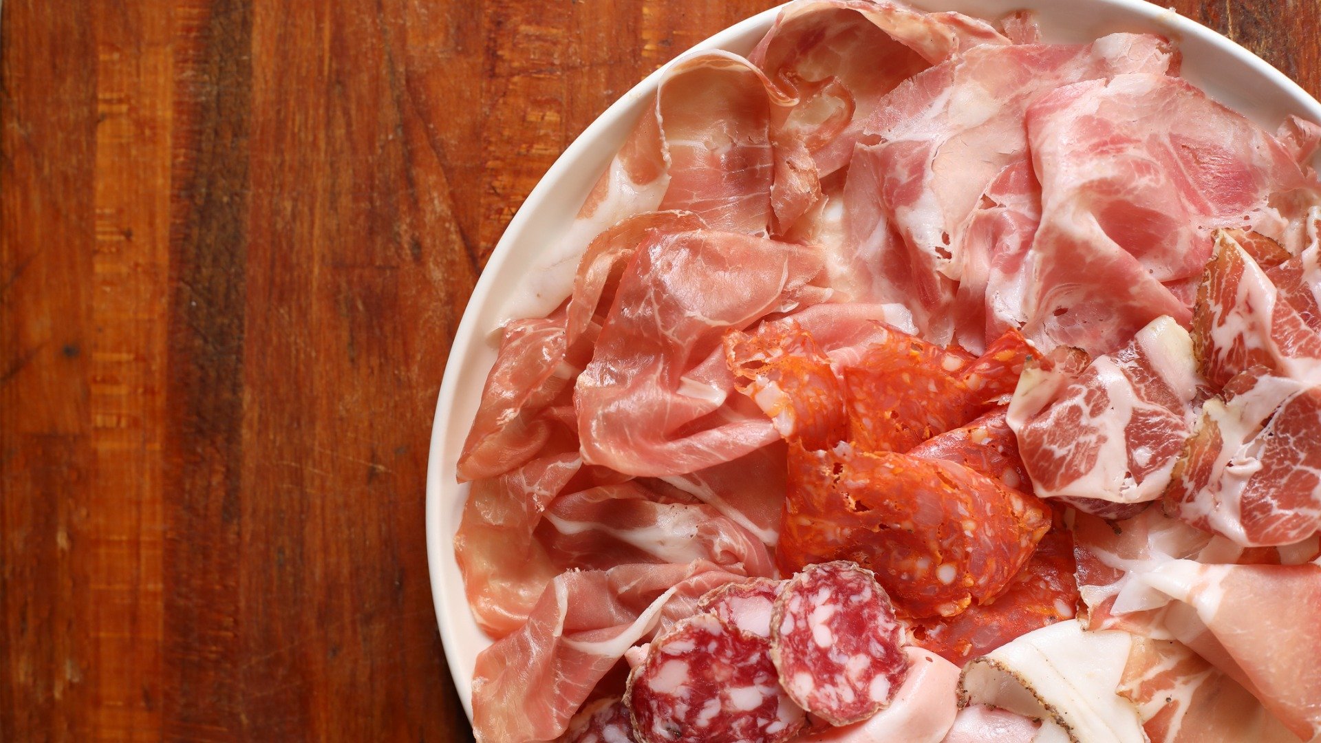 This is a plate filled with Italian cold cuts, like salami, prosciutto etc.