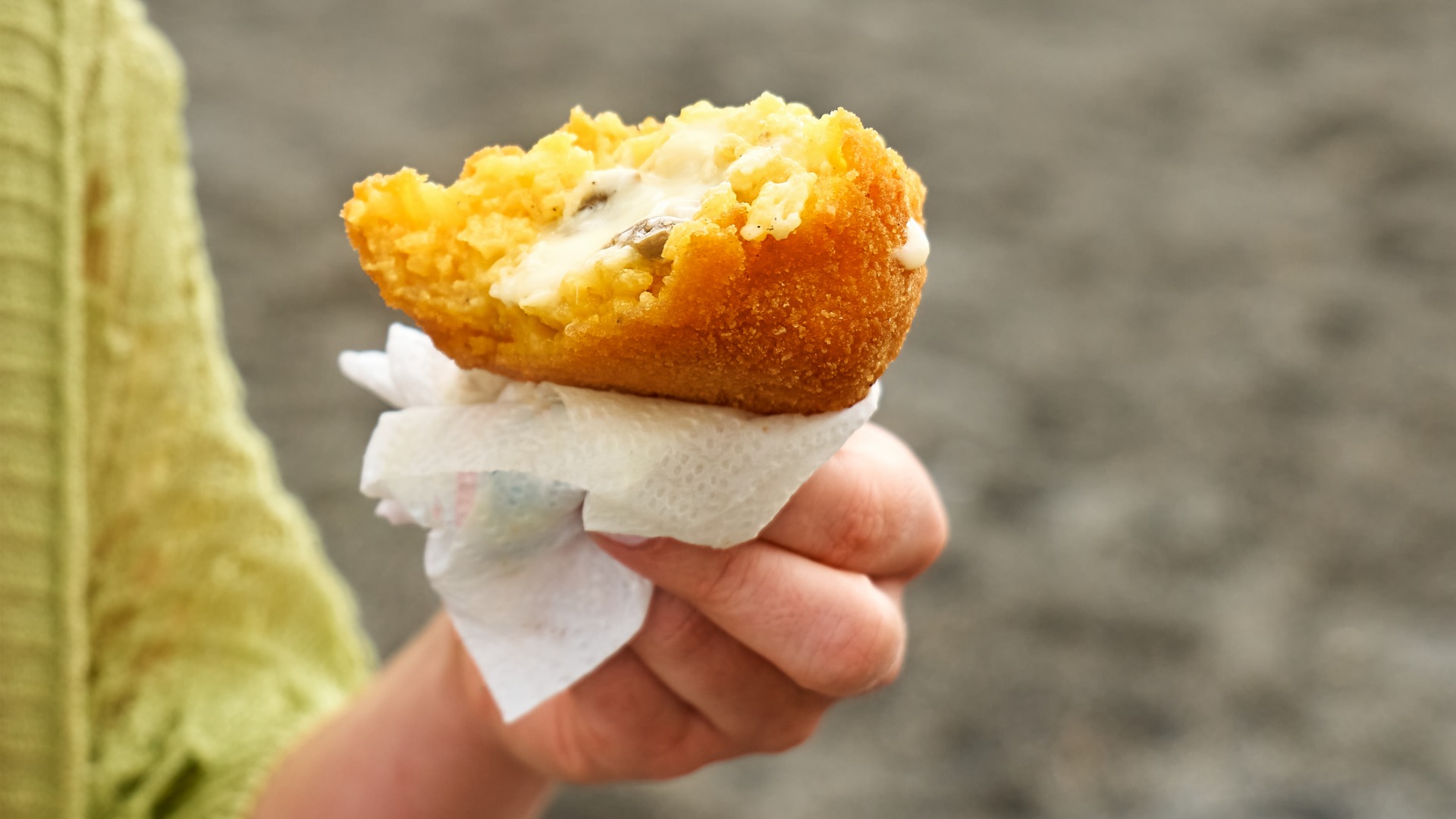 A woman's hand holding an Arancino.