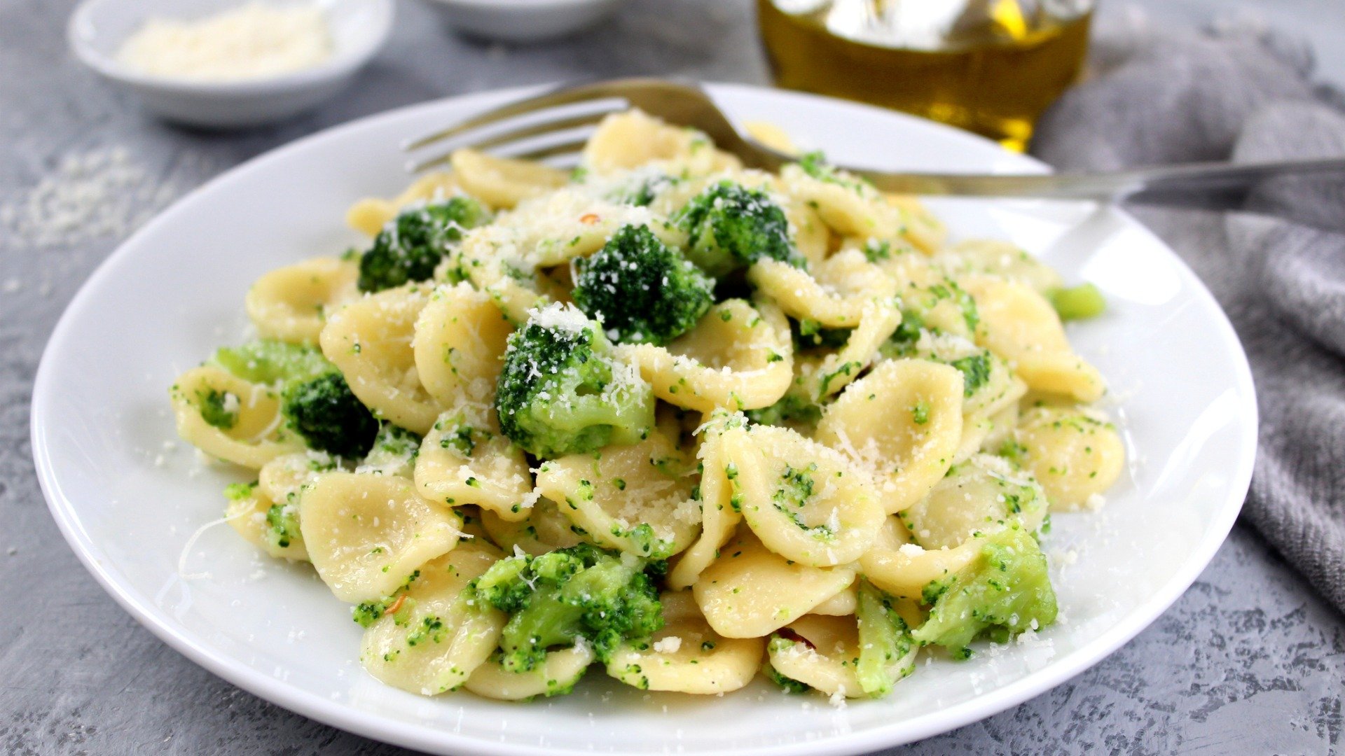 A dish of Orecchiette pasta with broccoli and grated Parmiggiano cheese.