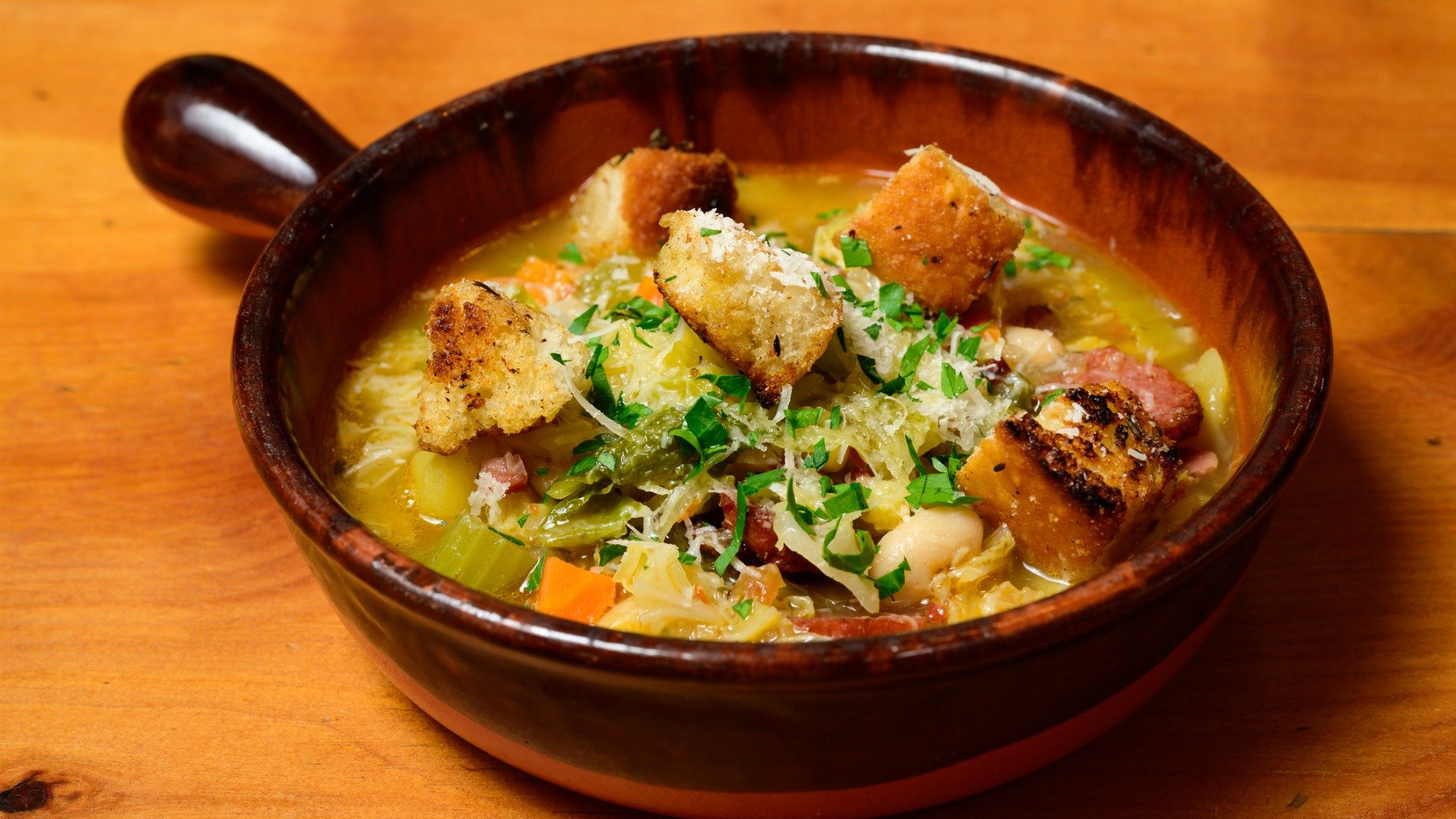 A close up of a Terracotta bowl with Ribollita bread and bean soup from Tuscany.