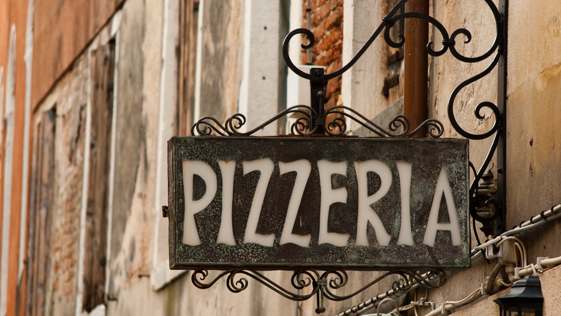 A close up of a Pizzeria iron cast sign.