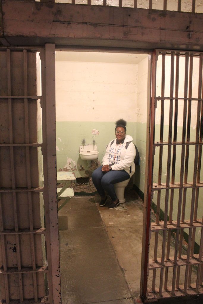 Pamela Pascal seated on the toilet in Al Capone's Alcatraz Cell B-181 - later renumbered to B-206.