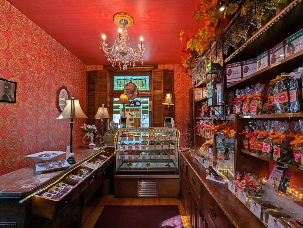 Inside Ridgway Confections, with a chandelier, red wallpaper and shelves lined with chocolate treats.