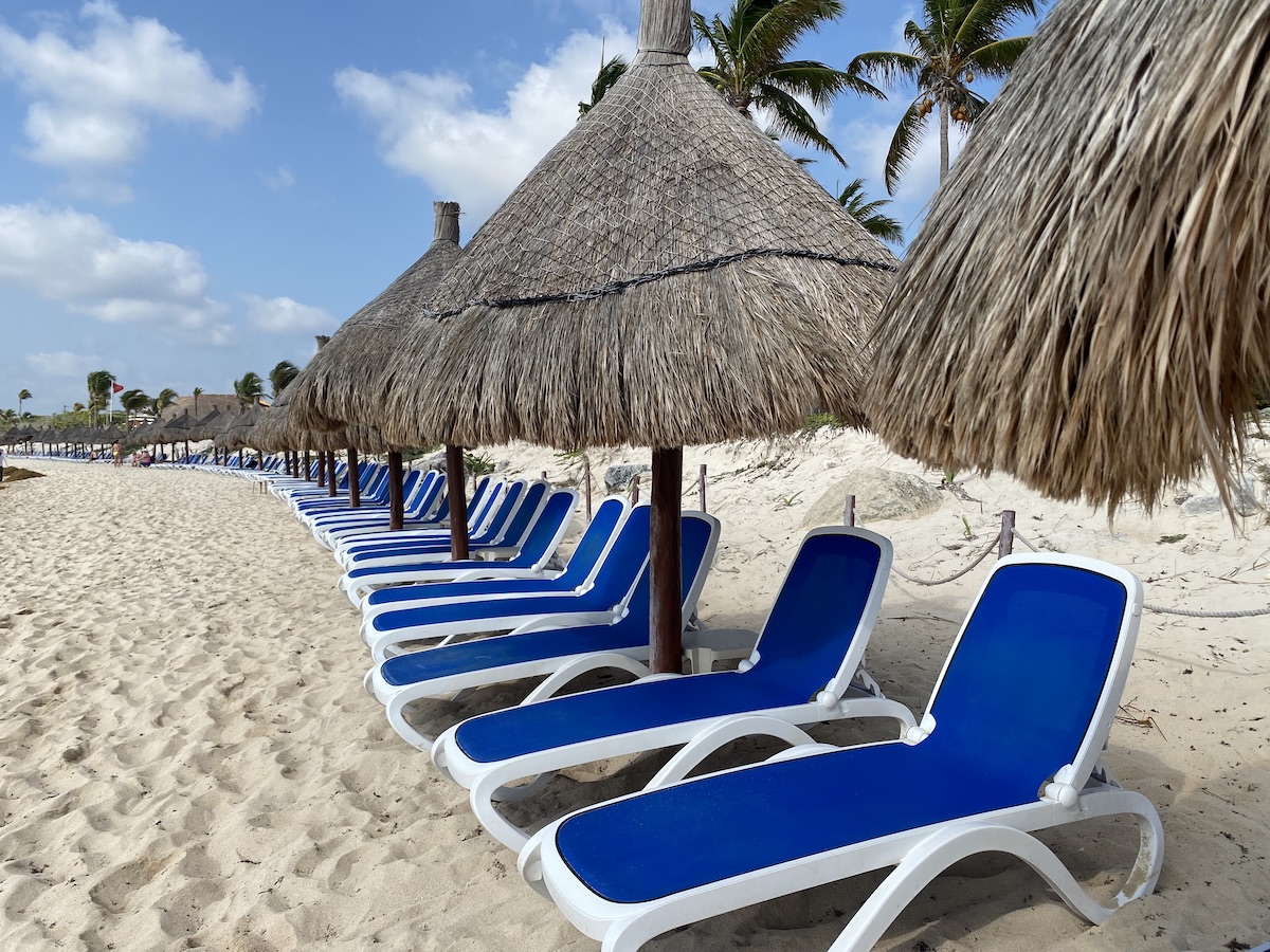 Row of blue lounge chairs on a beach on the Riviera Maya.