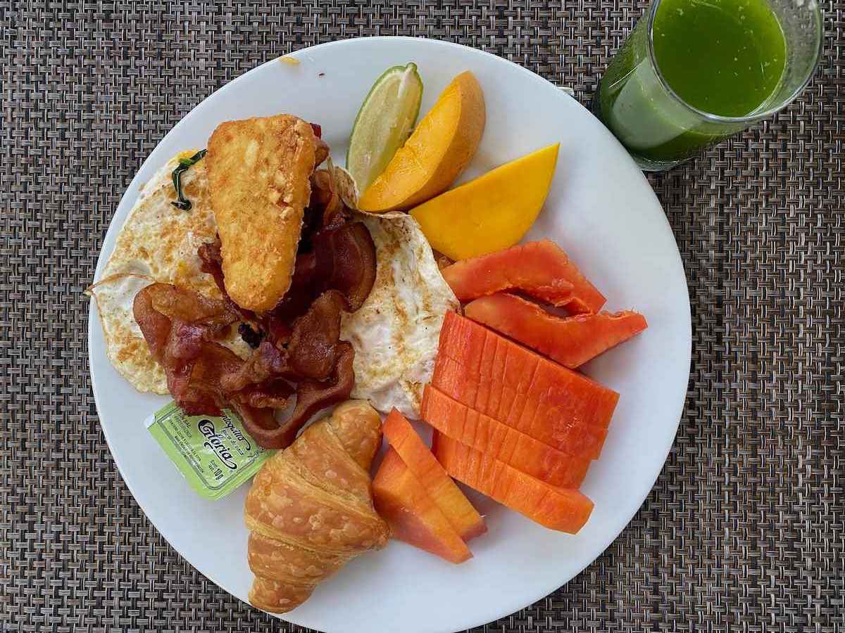 Breakfast with green juice, fruit, and bacon.