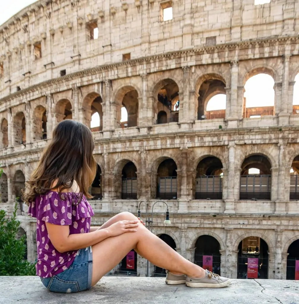 Kate Storm sitting in front of the Colosseum, a top attraction during a Rome itinerary