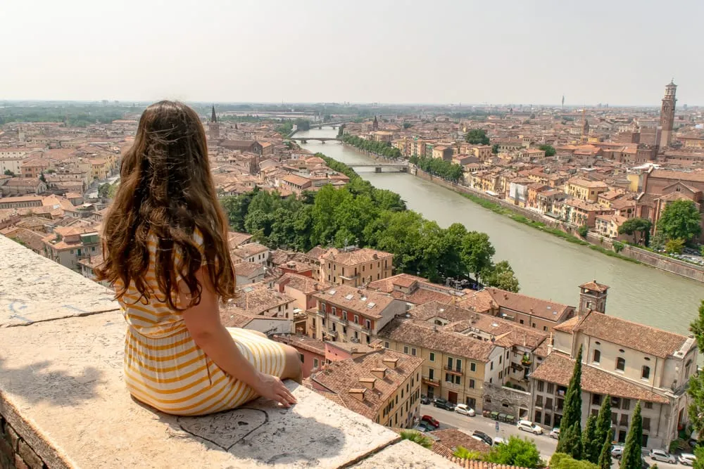 Kate Storm sitting on a wall overlooking Verona, Italy