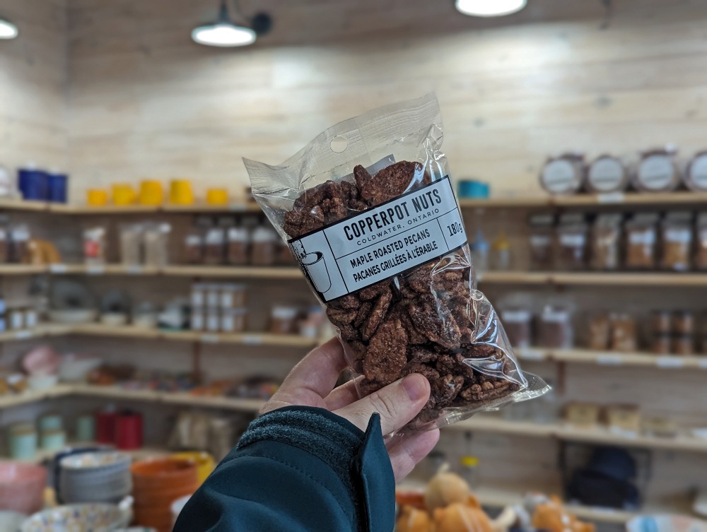 Copperpot Nuts bag of Maple Roasted Pecans being held up in the store