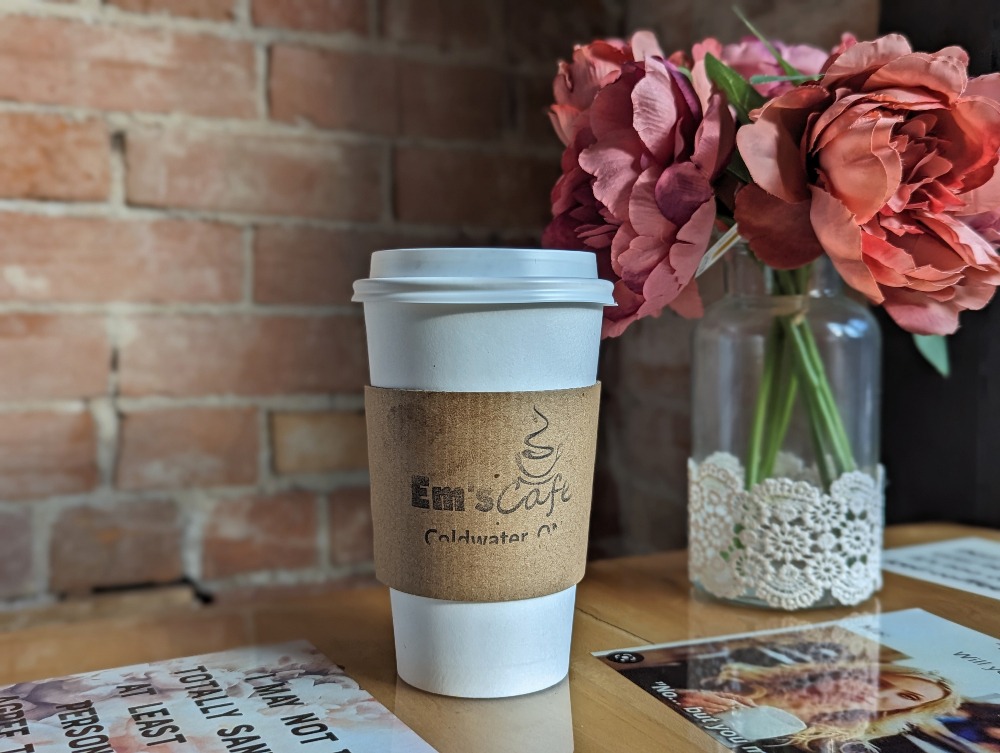 Coffee cup on a shelf with a flower bouquet beside it in Em's Cafe in Coldwater Ontario