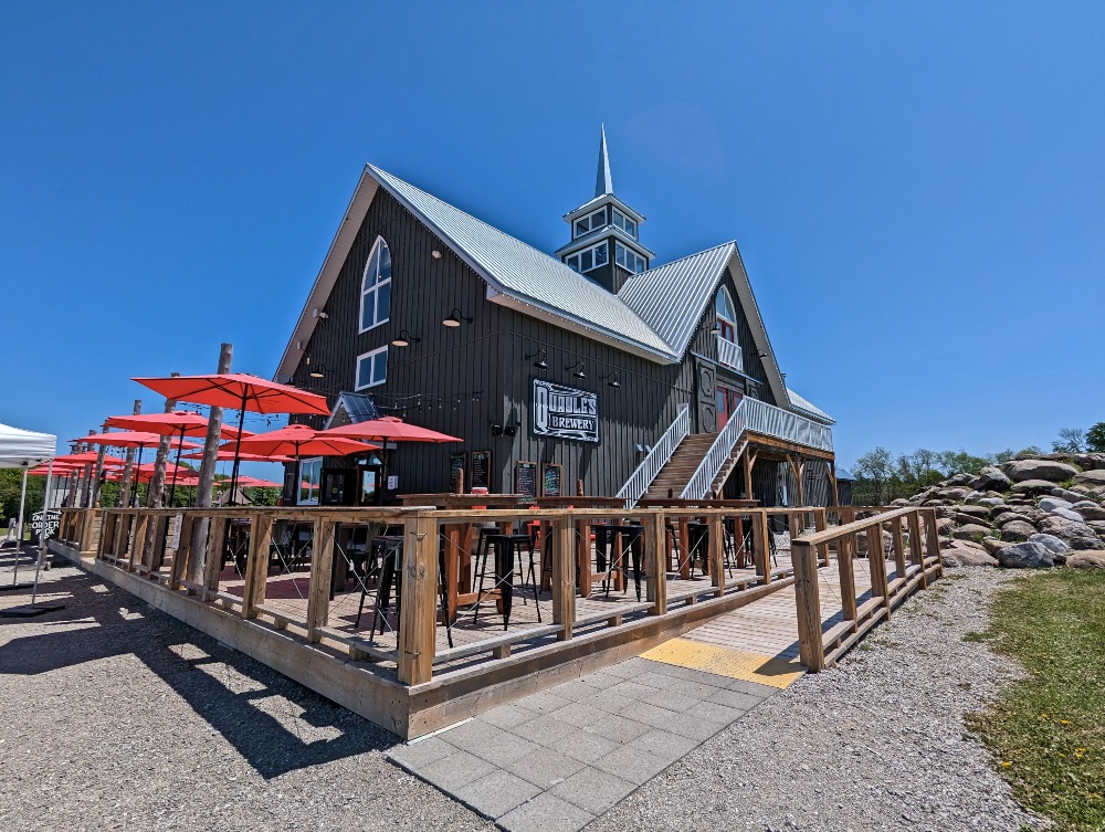 Exterior of Quayle's Brewery, resembling an old barn with a large patio and red umbrellas