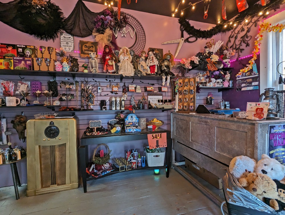 Inside the Dark Bazaar shop in Coldwater. There are shelves lined with unusual items like dolls, candles, and Halloween decor