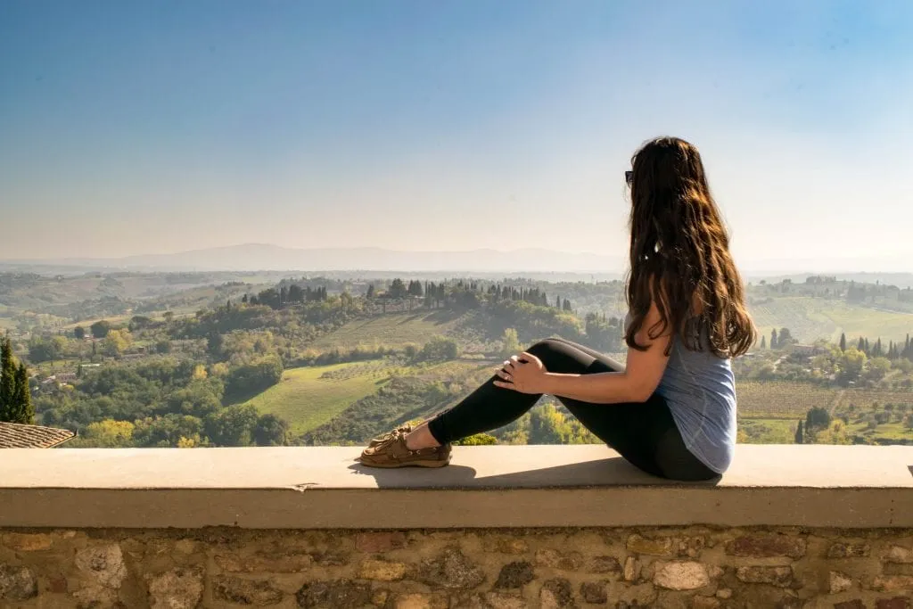 Kate Storm enjoying the picturesque Tuscan countryside from San Gimignano in the fall, one of the best stops on a 3-day Tuscany itinerary