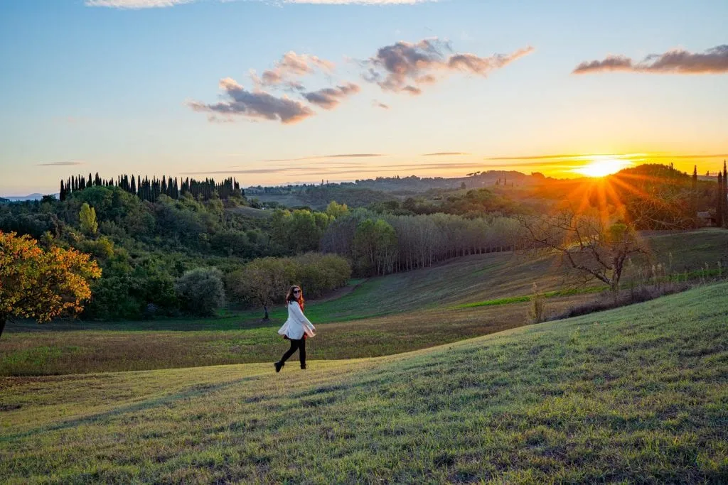 Kate Storm in the Tuscan countryside at sunset, with a sun flare on the right side of the photo.