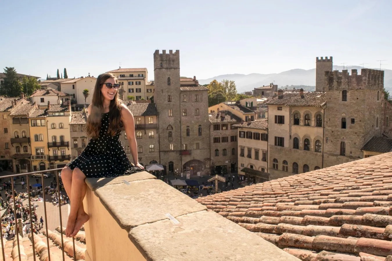 Kate Storm resting on a ledge overlooking Arezzo, a great day trip from Florence