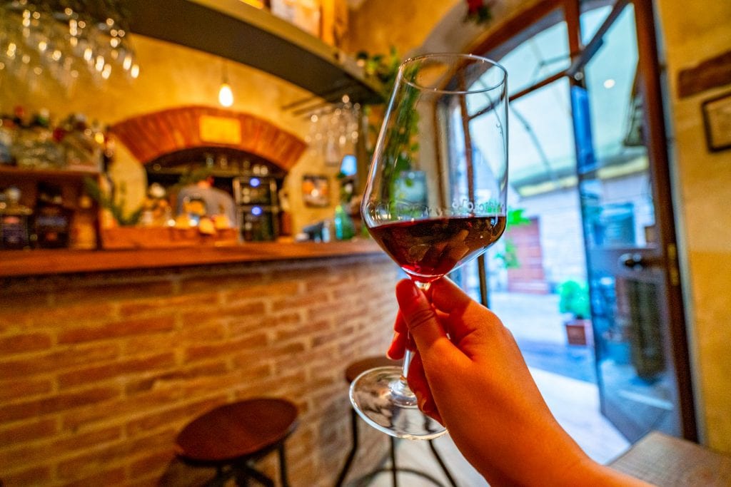 Hand holding up a glass of Vino di Nobile at a wine bar in Montepulciano, Italy