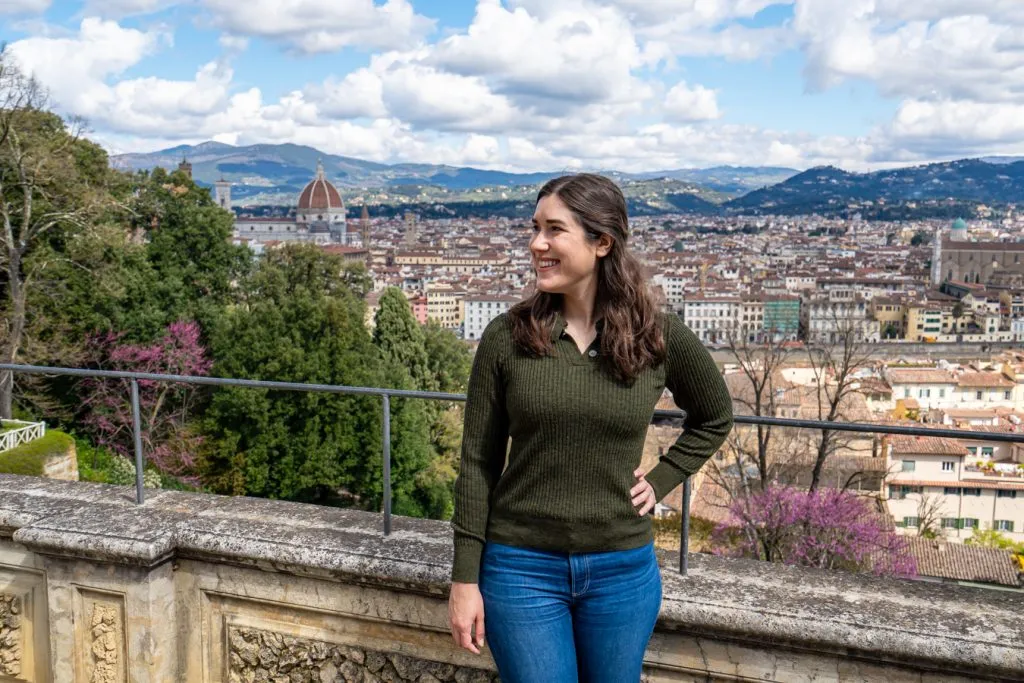 Kate Storm in a green sweater at the Bardini Gardens, with a view of Florence behind her