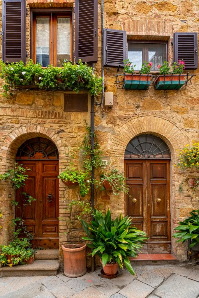 Beautiful front facades of houses complemented by lush greenery in Pienza, Italy