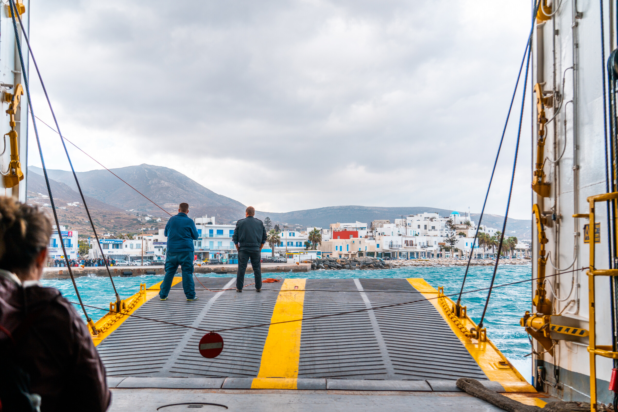 Passengers waiting at the open ferry door as it approaches Parikia Port in Paros.