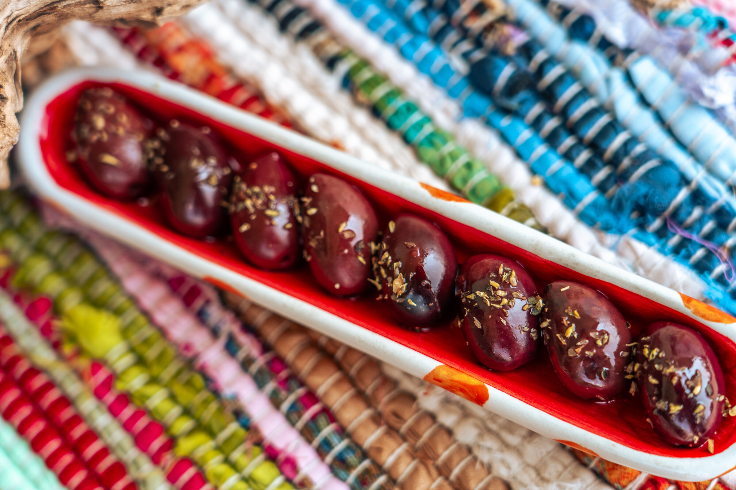 A close-up of sizable brown Kalamata olives garnished with oregano.