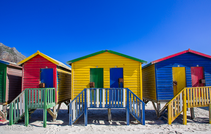 three vibrant multicolored beach houses at Muizenberg Beach