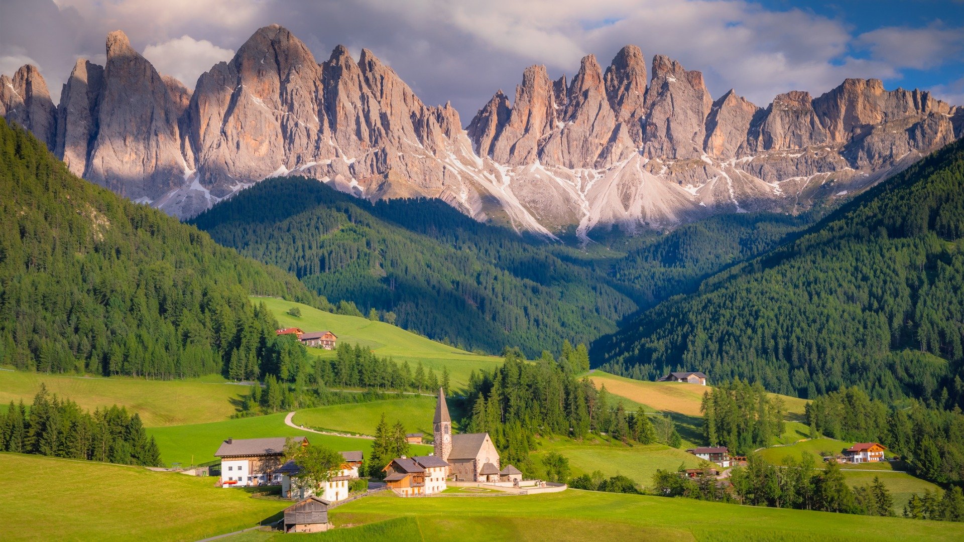 This is a panoramic view of the village of Santa Magdalena with the peaks of the Dolomite Mountains in the background.