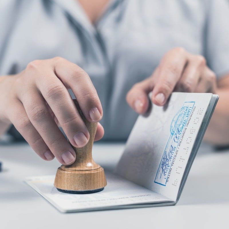 A Female Immigration Officer Stamping A Passport At Border Control, International Travel