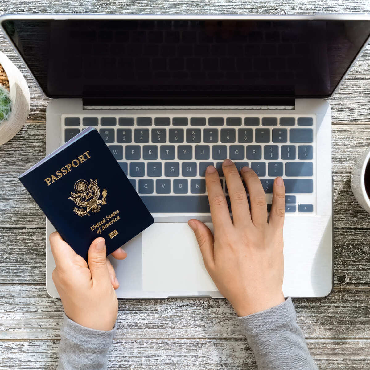 American Traveler Using Their Computer While Holding A U.S. Passport