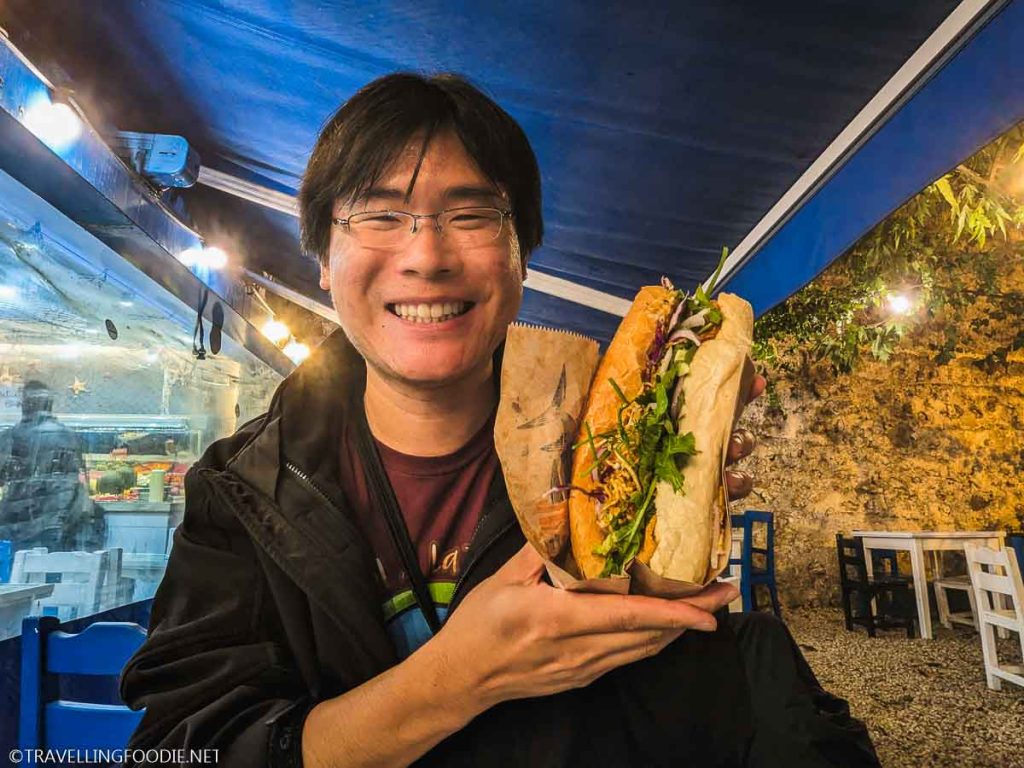 Travelling Foodie Raymond Cua holding whiting fish sandwich