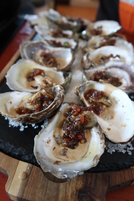 Grilled oysters in a black garlic cream sauce with bacon jam