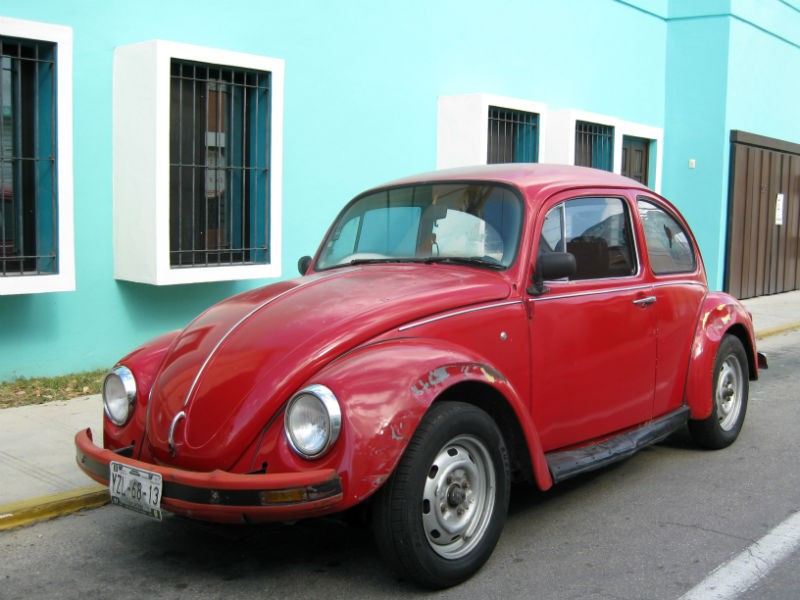 Mérida Red VW Bug car Blue outside an aqua blue House