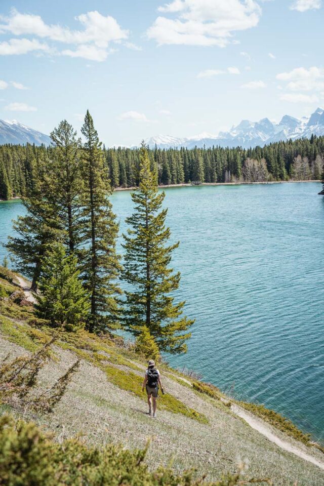 Person walking along a mountain trail by the lake, one of the best hikes in Banff for beginners