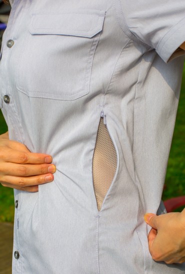 Woman displays the meshed side vents of the Mark’s No Fly Zone mosquito repellent shirt made of permethrin.