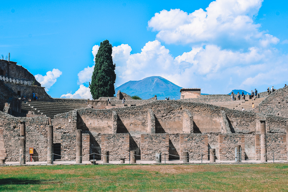 Exploring the Gladiator Barracks at the Quadriportico dei Teatri in Pompeii, with Mount Vesuvius in the background