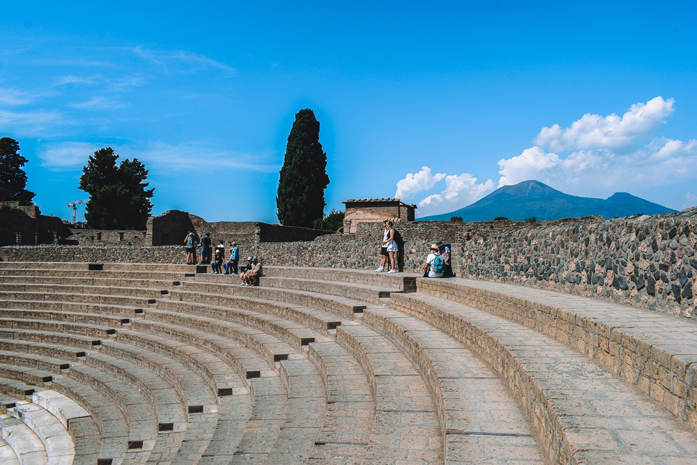 Exploring the Teatro Grande of Pompeii with Mount Vesuvius in the background