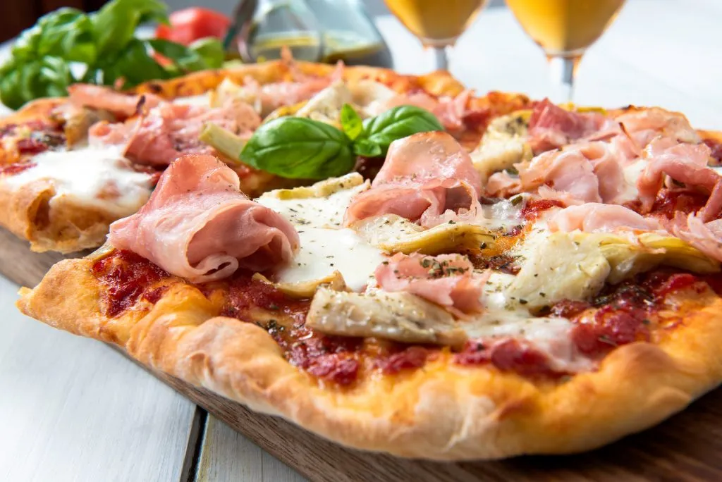 Pizza alla pala on a table with greens and drinks