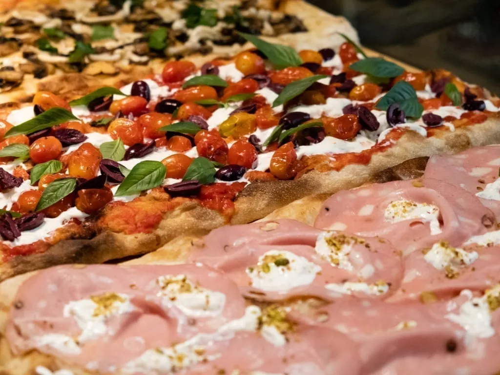 Pizza al Taglio presented in pans, with a mortadella flavor in the front