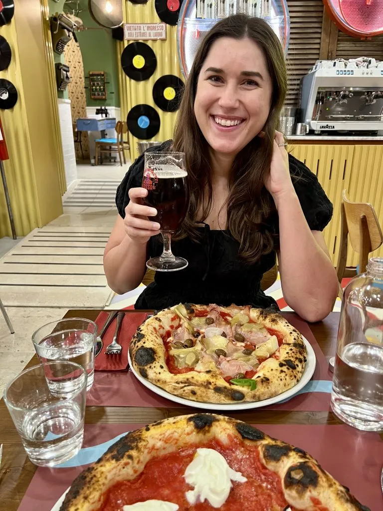 Kate Storm enjoying a Capricciosa pizza in Italy with a beer