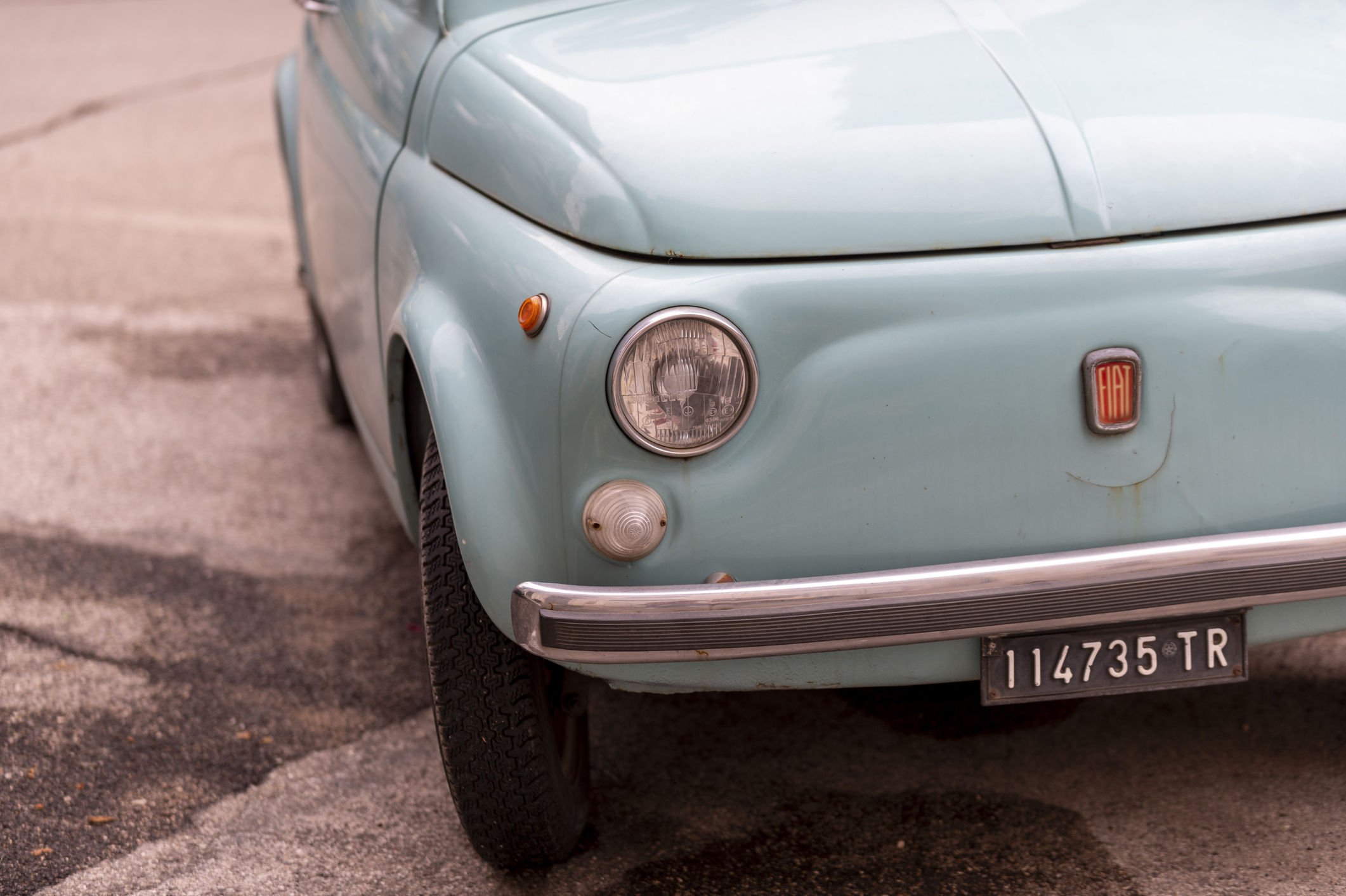 A close-up of a vintage light blue Fiat 500.