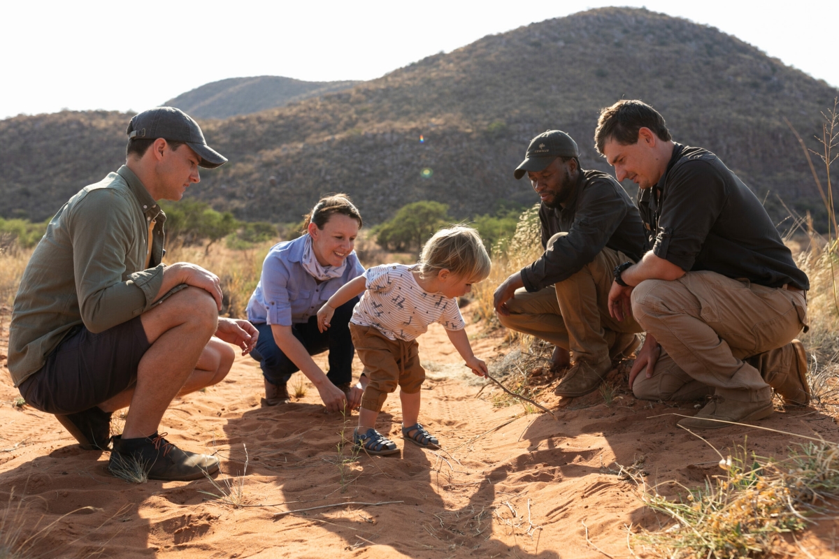 Family and guide showing an infant animal tracks in the sand