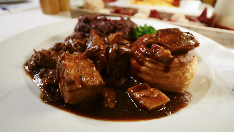 Venison stew served with cabbage, a puff pastry, a pear and cranberry sauce