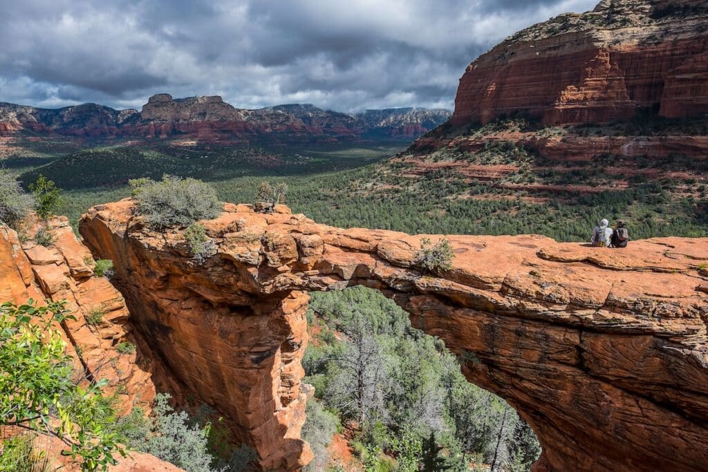 Two hikers sitting on top of Devil's Bridge in Sedona