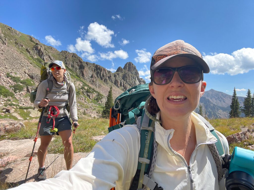 Two people backpacking in the mountains on a sunny day.