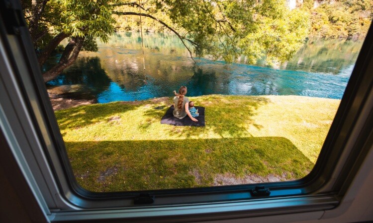 A mom and child enjoying time by the river outside their motorhome