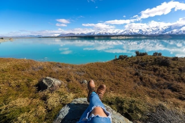 A person sitting on rocks with Lake Pukaki in the background