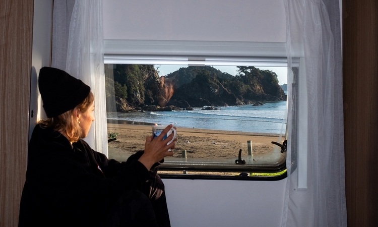 A woman enjoying her coffee inside a motorhome while enjoying the view outside