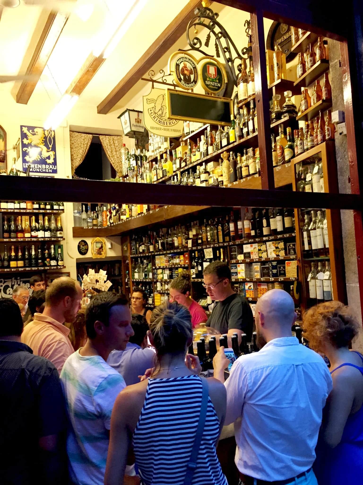 Interior of Quimet & Quimet, a popular tapas bar in Poble Sec, Barcelona, showcasing patrons mingling around the bar.