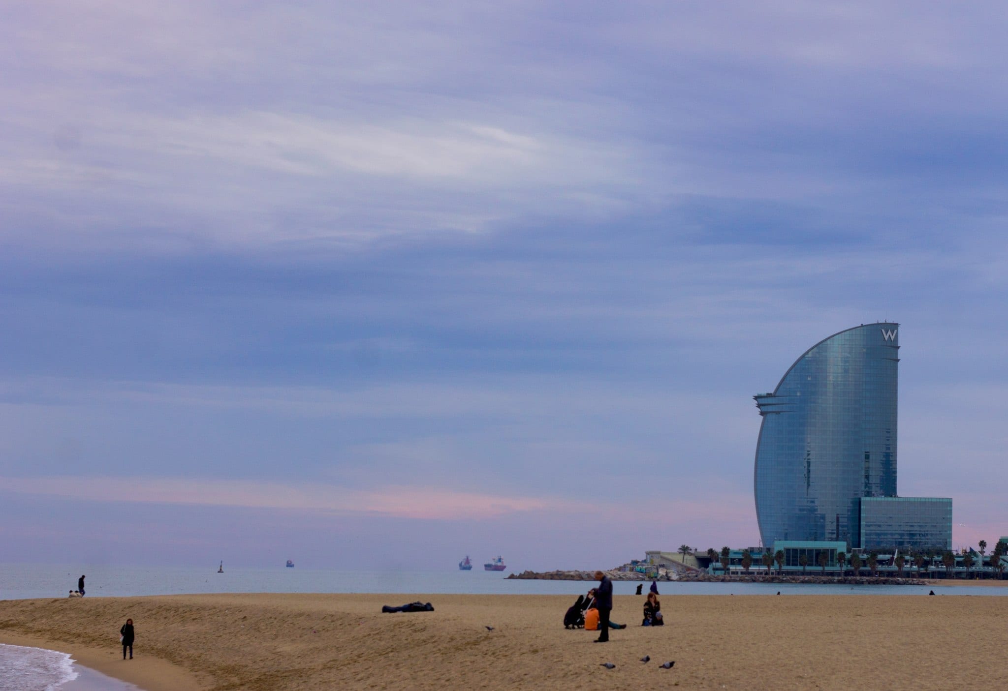 W Barcelona Hotel situated on the beach with people enjoying the seaside.